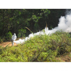 Operator in protective gear fogging in wilderness.